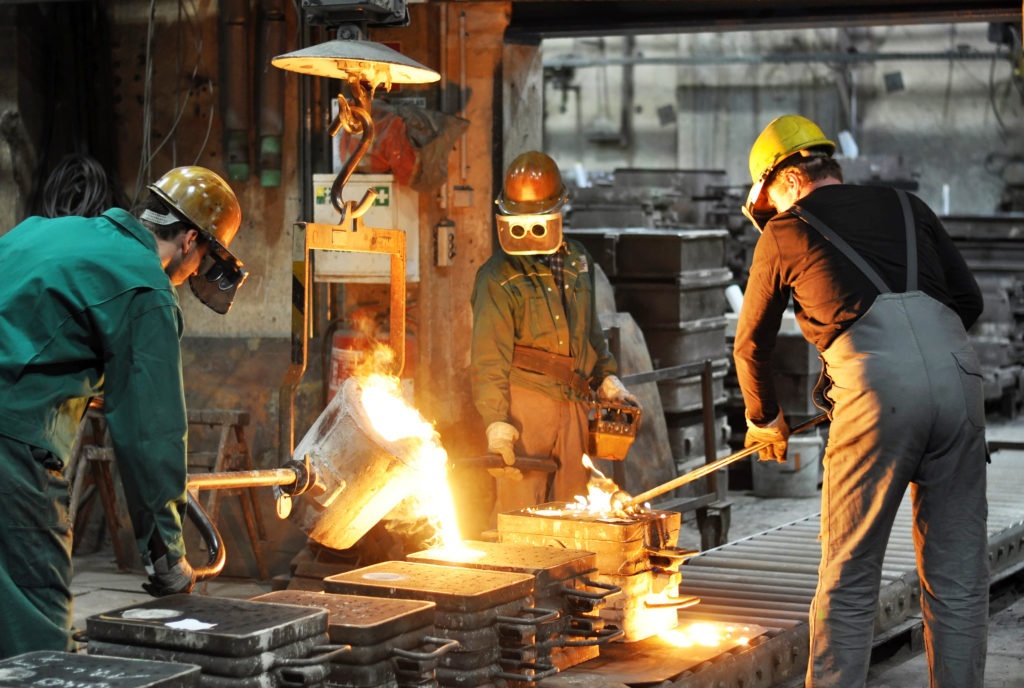 Three men handling molten metal in foundry